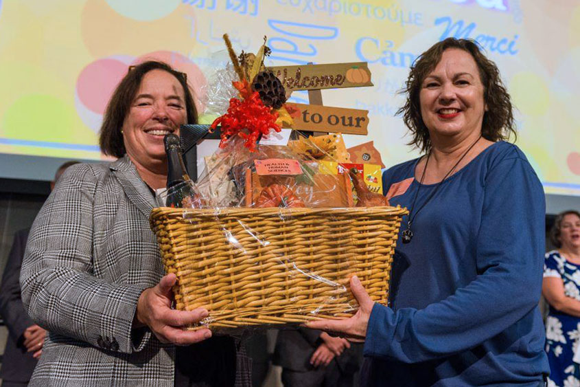 Two staff members holding up a gift basket.