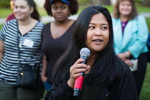 A SJSU community member holding a microphone and speaking to the public on campus.
