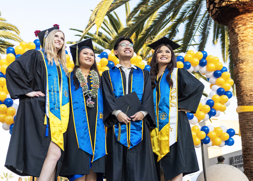 Grads pose together under the golden light outside the event center venue.