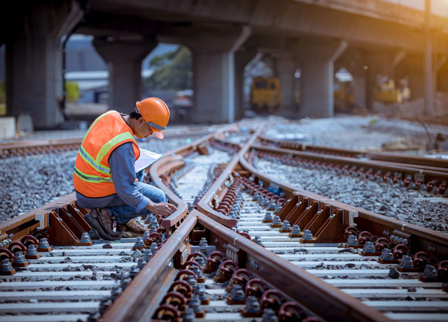 A railroad city worker inspecting railroad tracks.