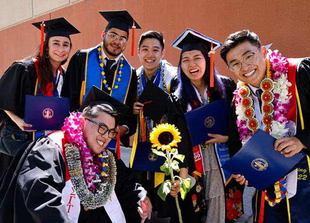 SJSU graduates pose in front of the event center in celebration.