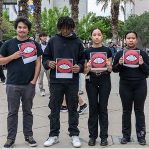 Students holding print ads that promote the production.
