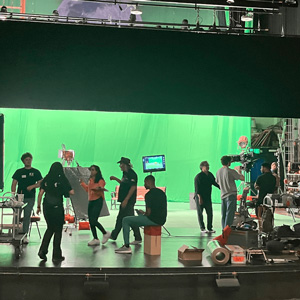 Film students working in SJSU’s University Theatre stage with a green screen behind them.