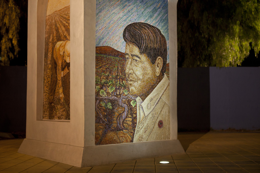 A mural of César Chávez is light warmly at night on SJSU's César Chávez Arch.