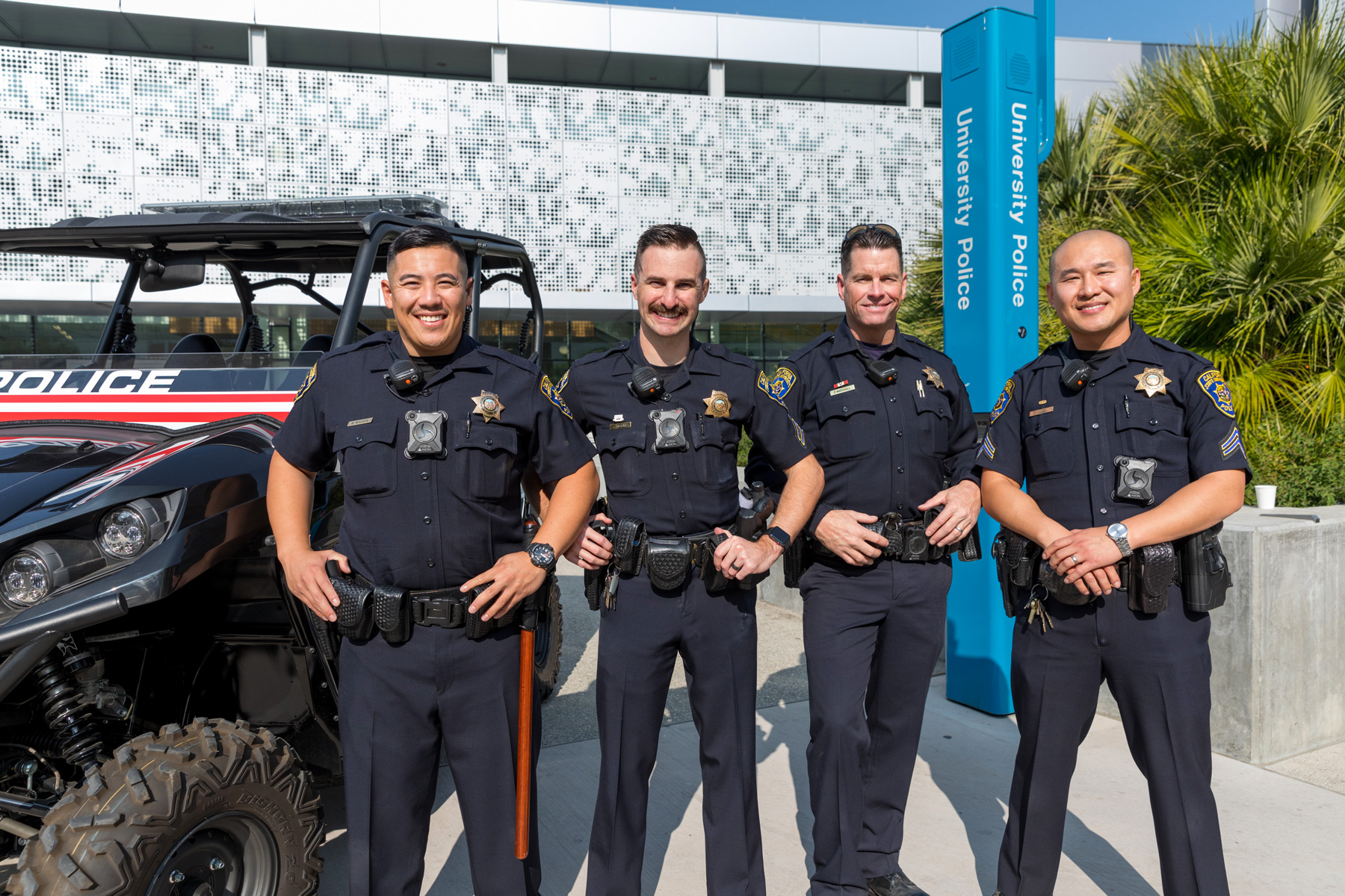 A group of SJSU campus cops pose with a smile on campus.