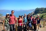 Nine staff are smiling at the camera.  The foreground has a view of the Golden Gate Bridge and the SF Bay.