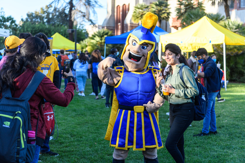 A student poses for a photo with Sammy Spartan during a campus event.