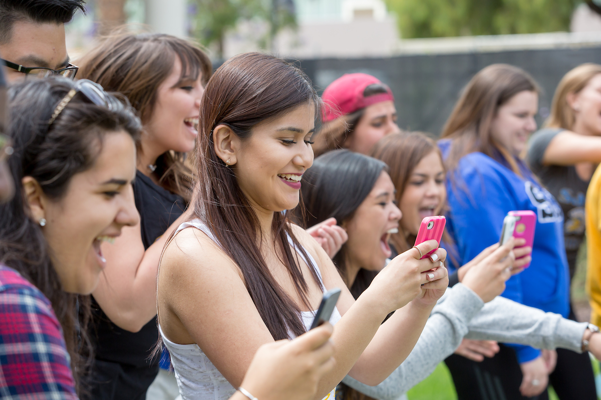Several students appear excited, all viewing their cellphones.