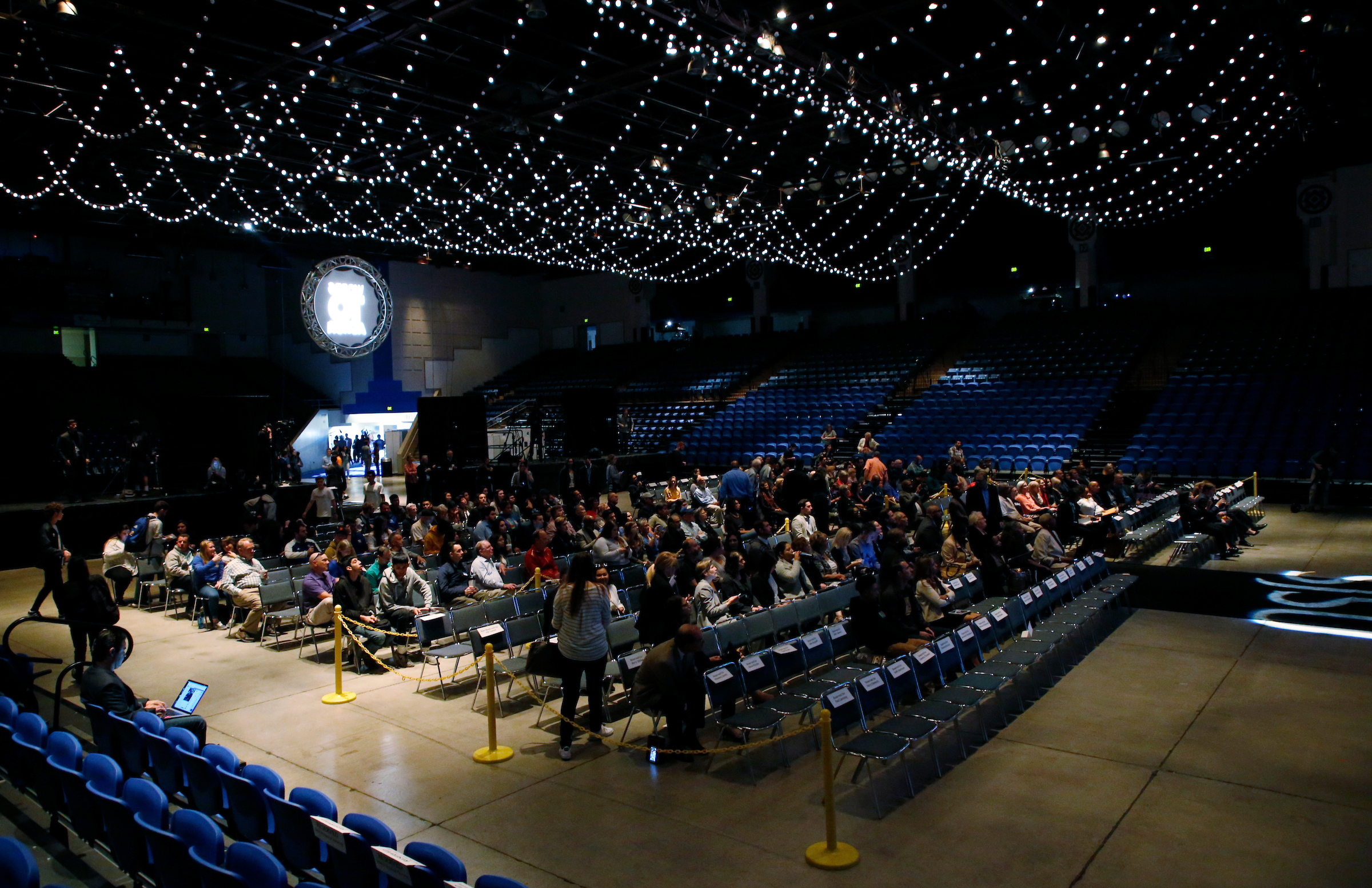 A crowd of people are seated inside a dark event center.