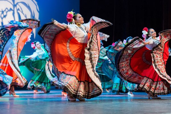 Women dancing, wearing colorful traditional Mexican regalia