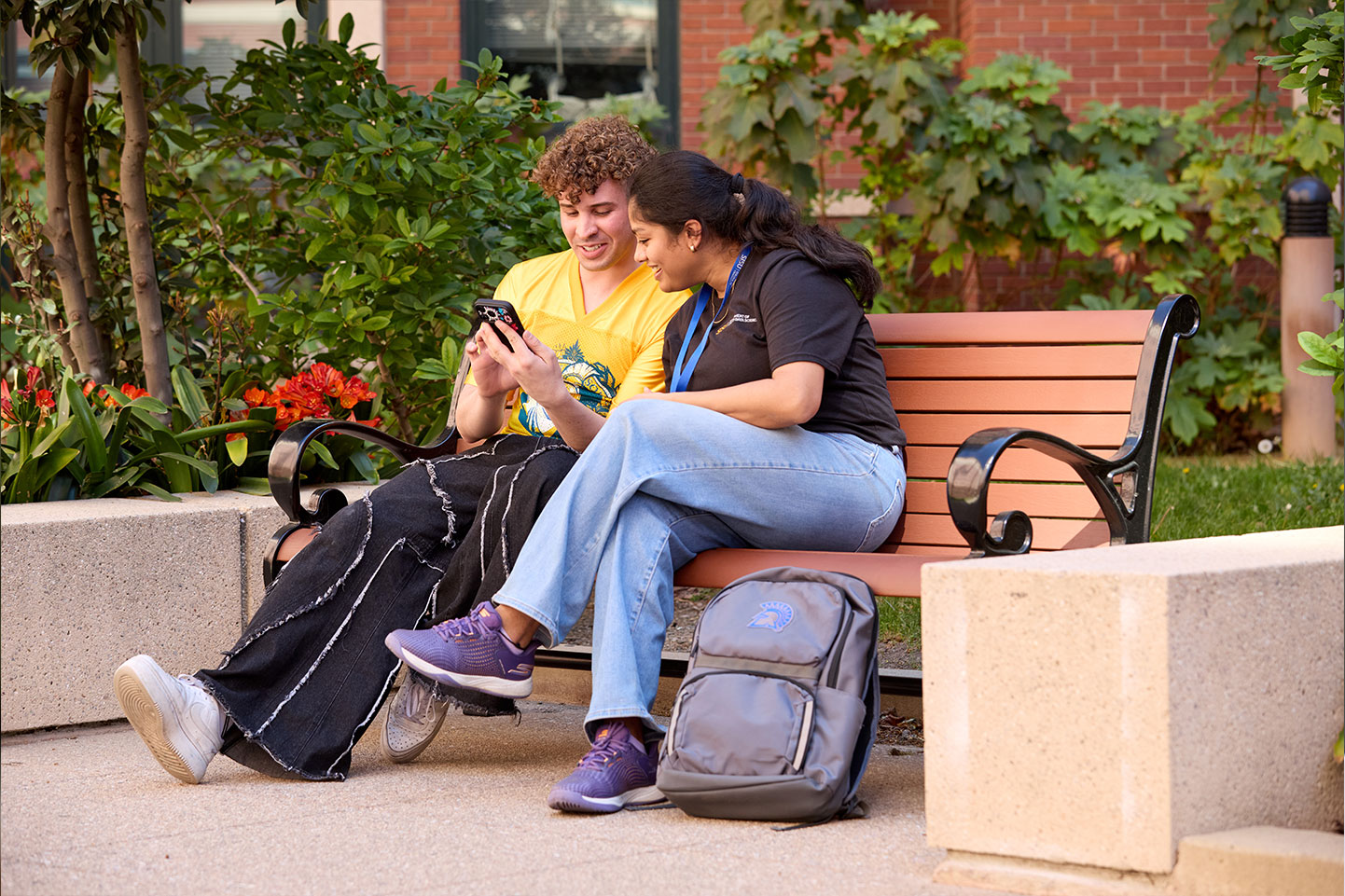 Students outside on a bench looking at a shared phone screen.