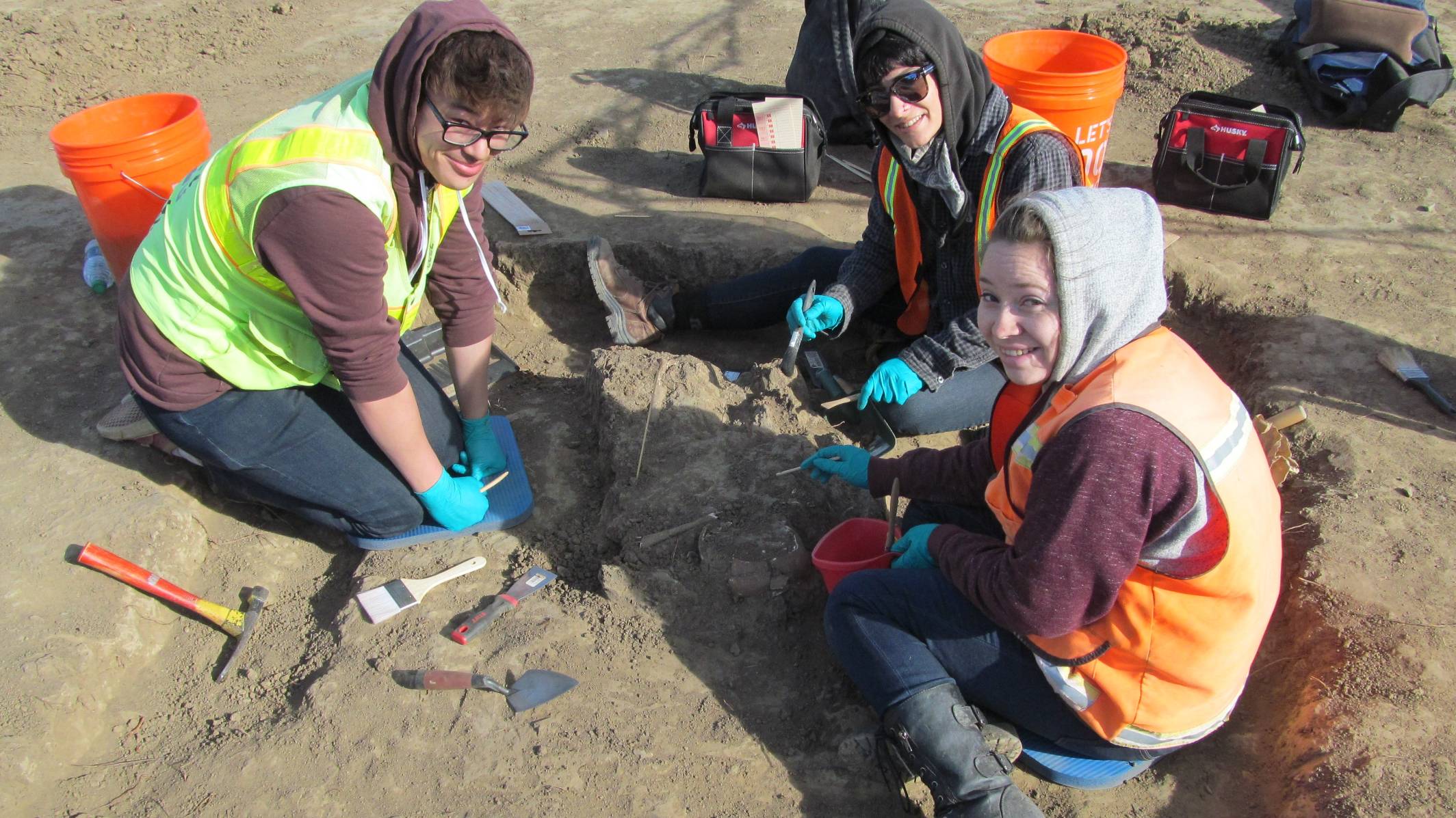 Three anthropolgy students working on a dig