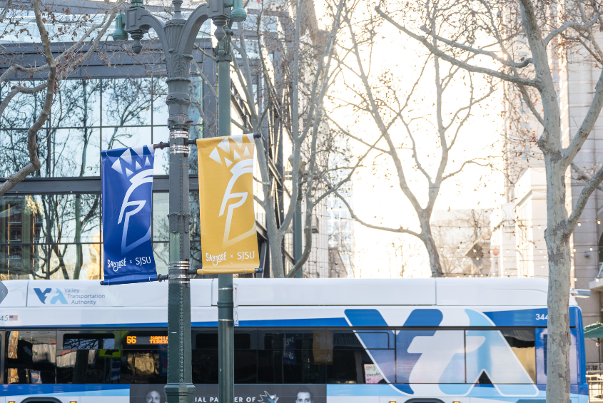 VTA bus driving by a set of SJSU branded banners in downtown San José.