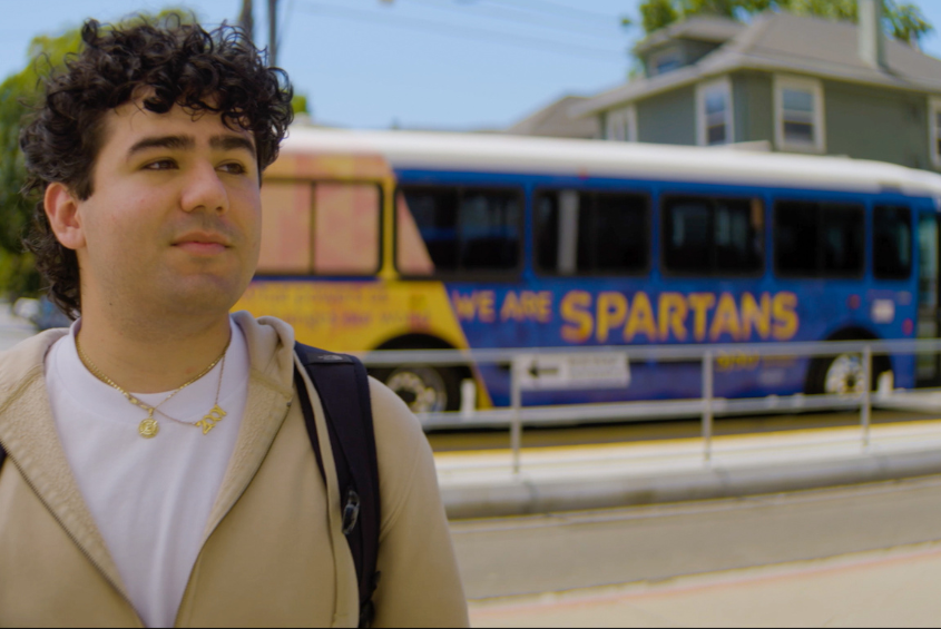 Student standing in front of the SJSU south campus parking shuttle.