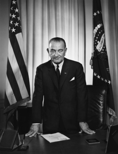 Lyndon B. Johnson standing over desk photo