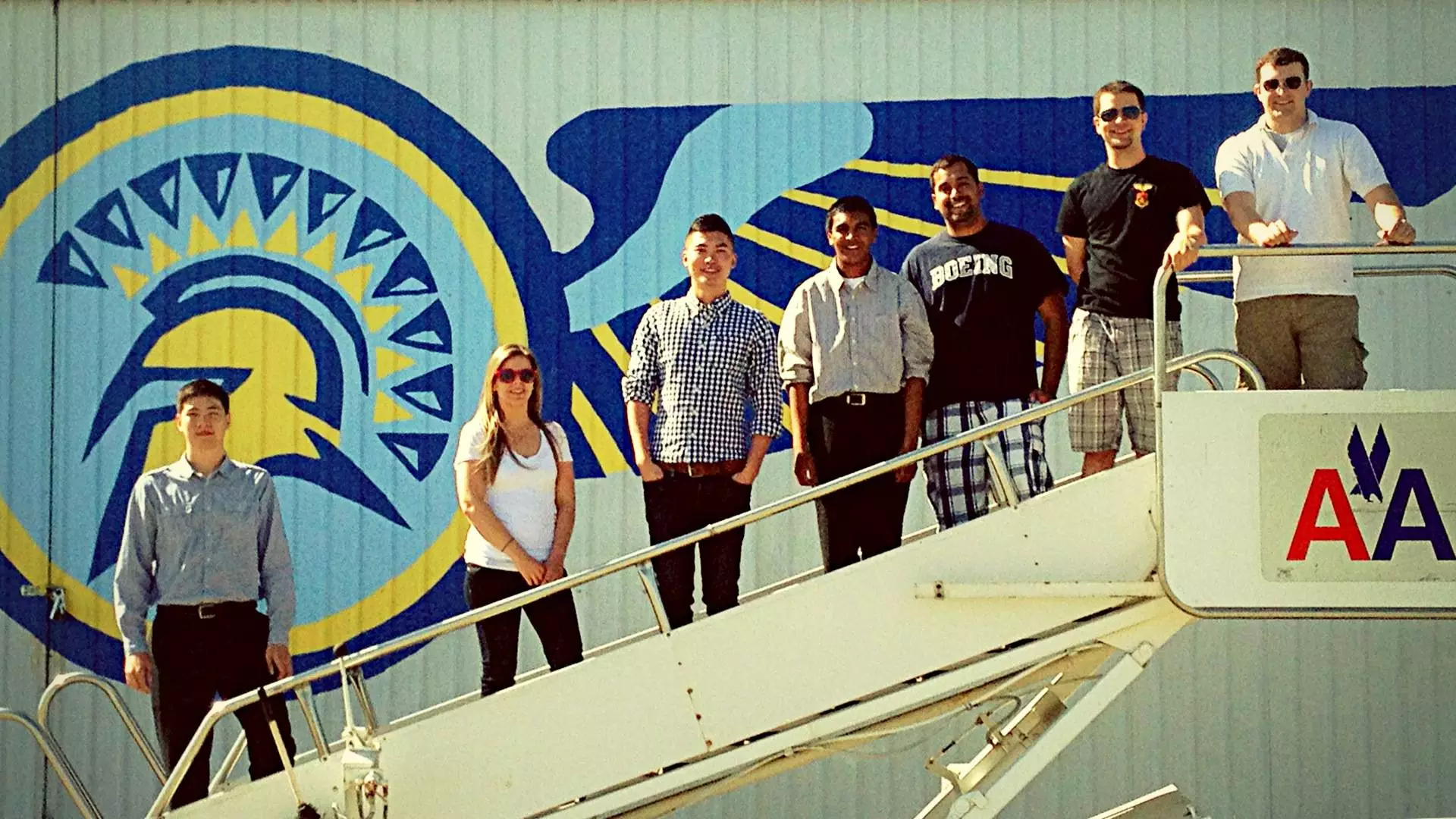 Aviation students posing on an airplane ramp.