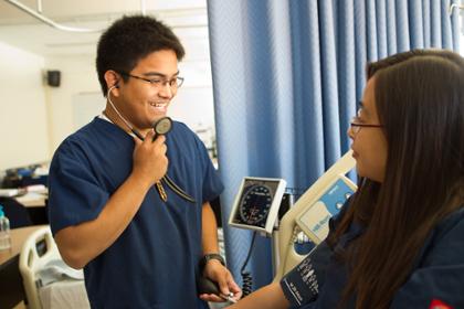 A nursing student takes blood pressure of another student.