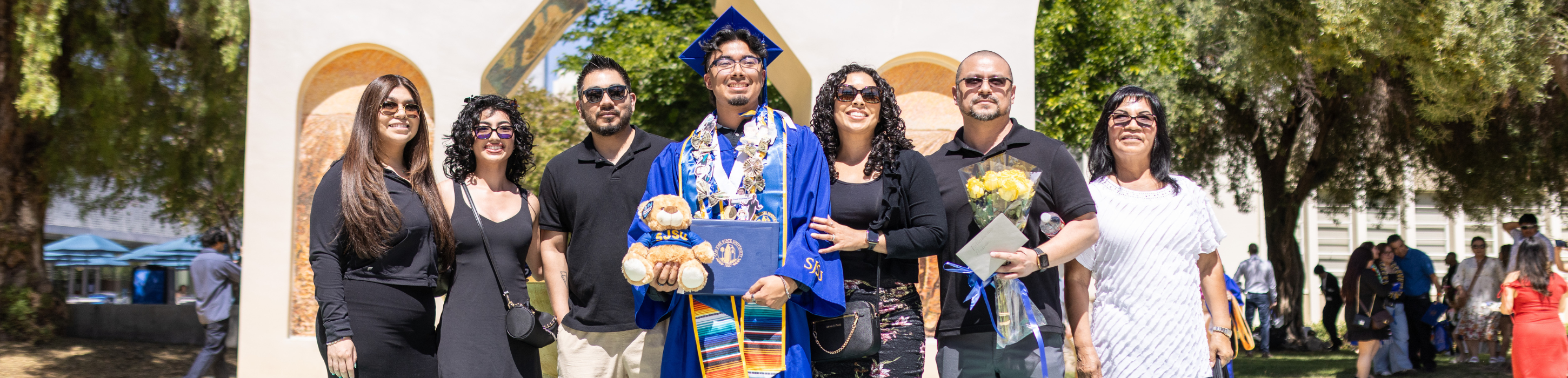 Graduating student posing with their family members in front of the Dignity Arch