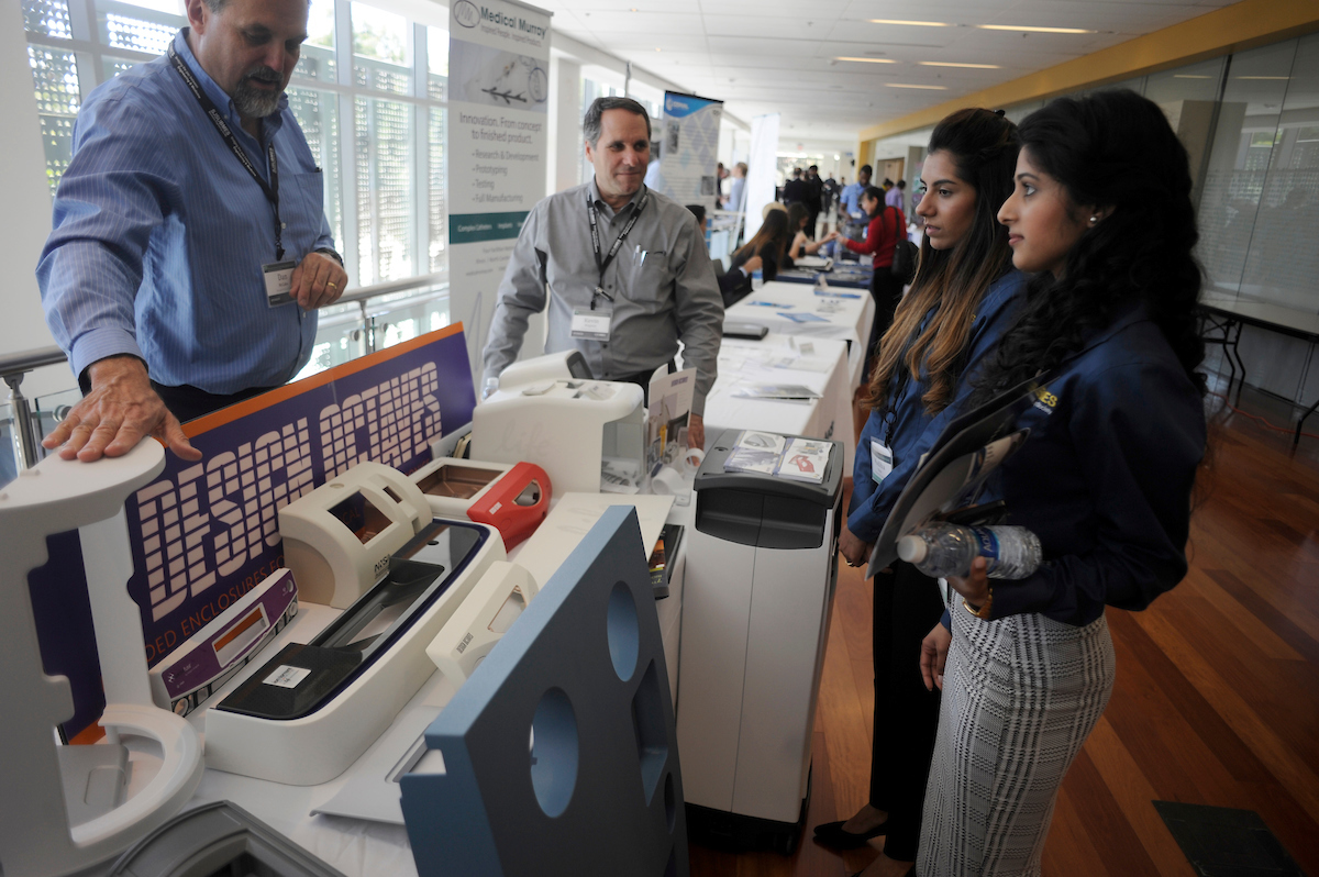 Students visit a table and listen to a vendor at the Biomedical Conference.