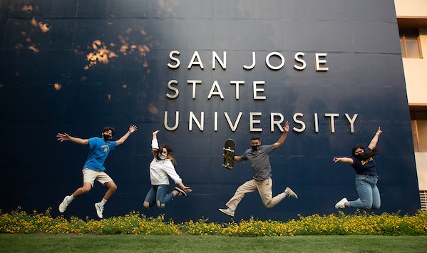 SJSU students jumping in joy in front of a 'San Jose State University' sign