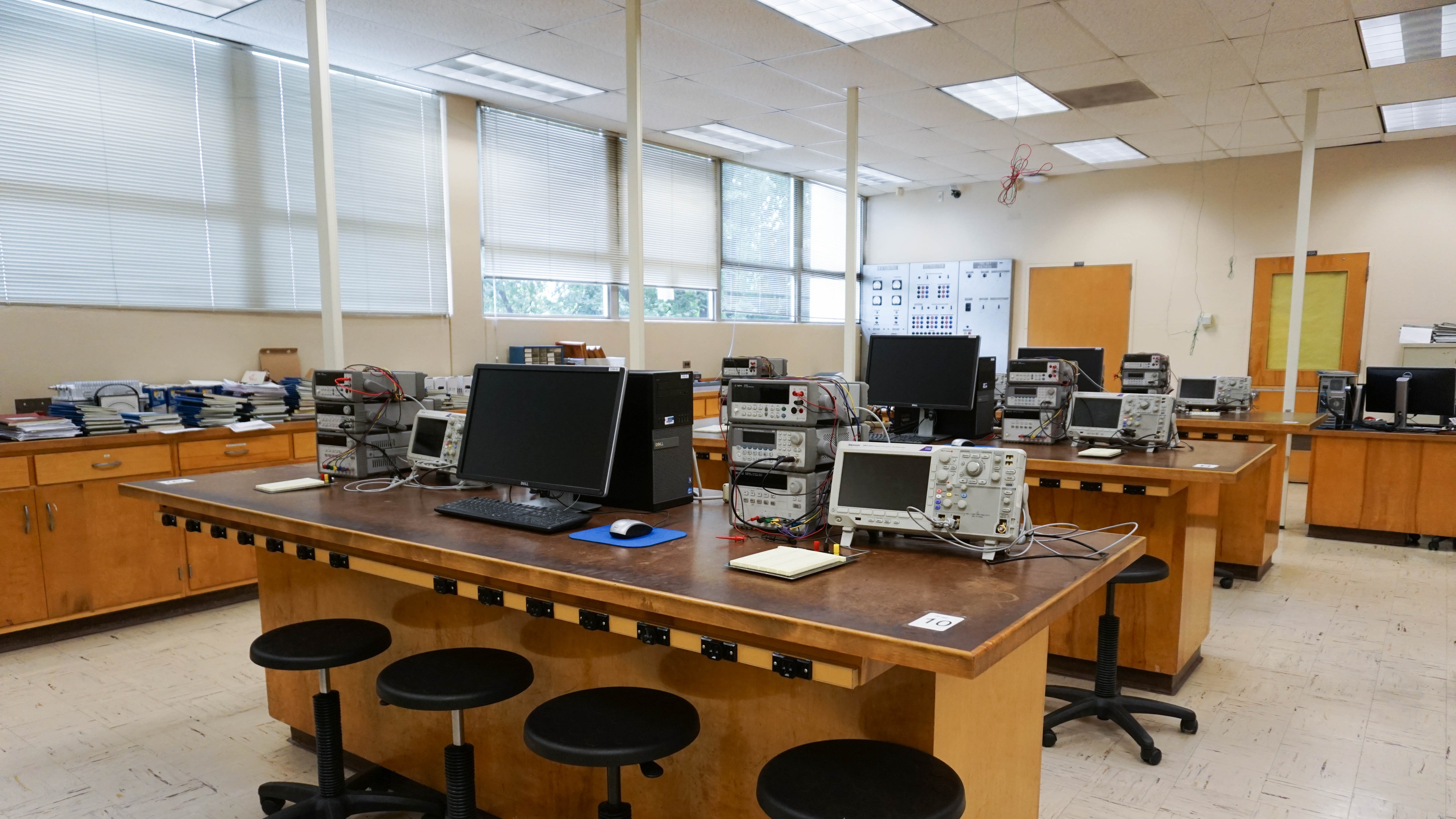 One of the lab's wooden desk with four stools for students to work with the equipment.
