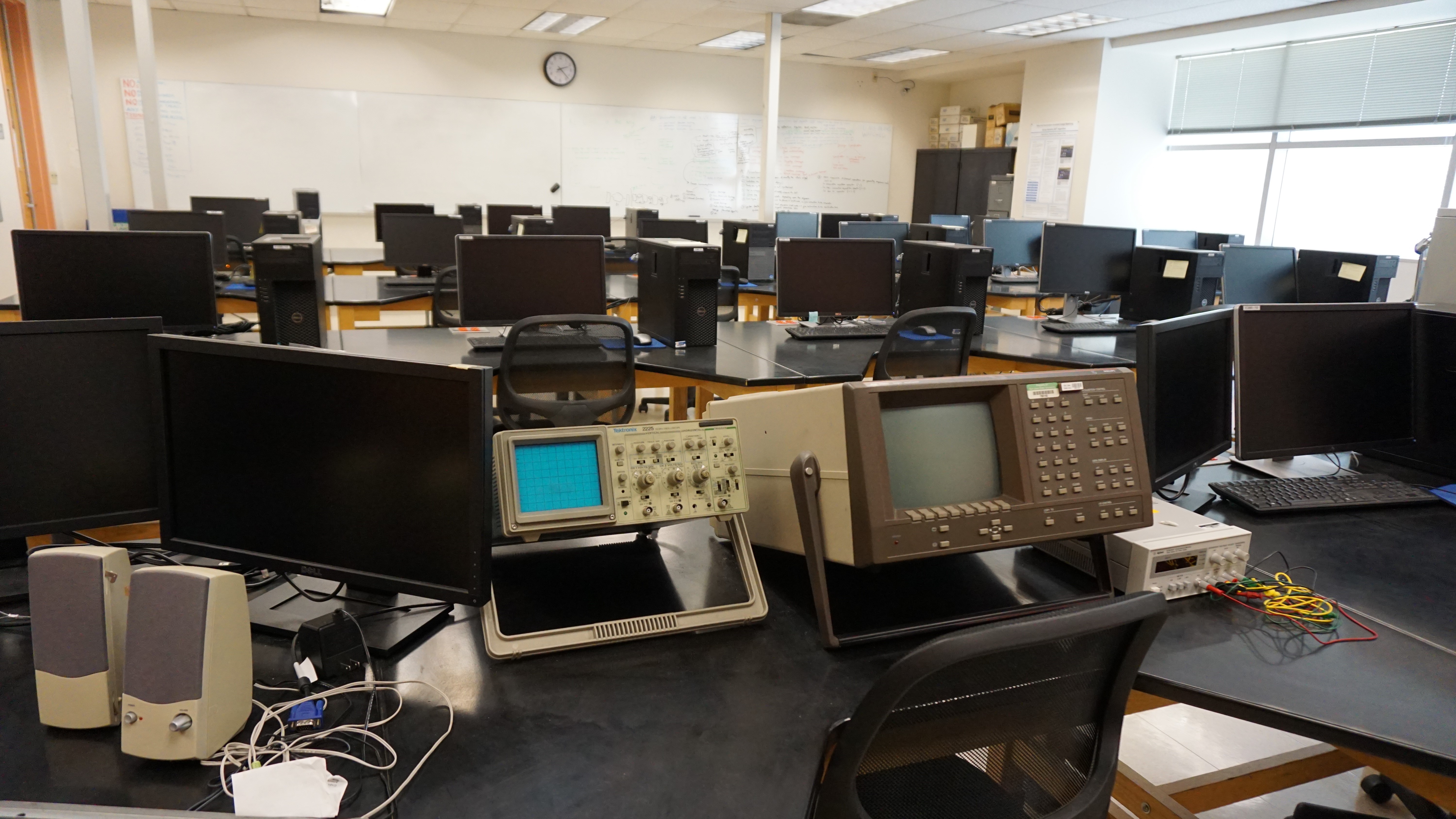 Rows of black monitors and a small bright blue screen on one of the lab machines.