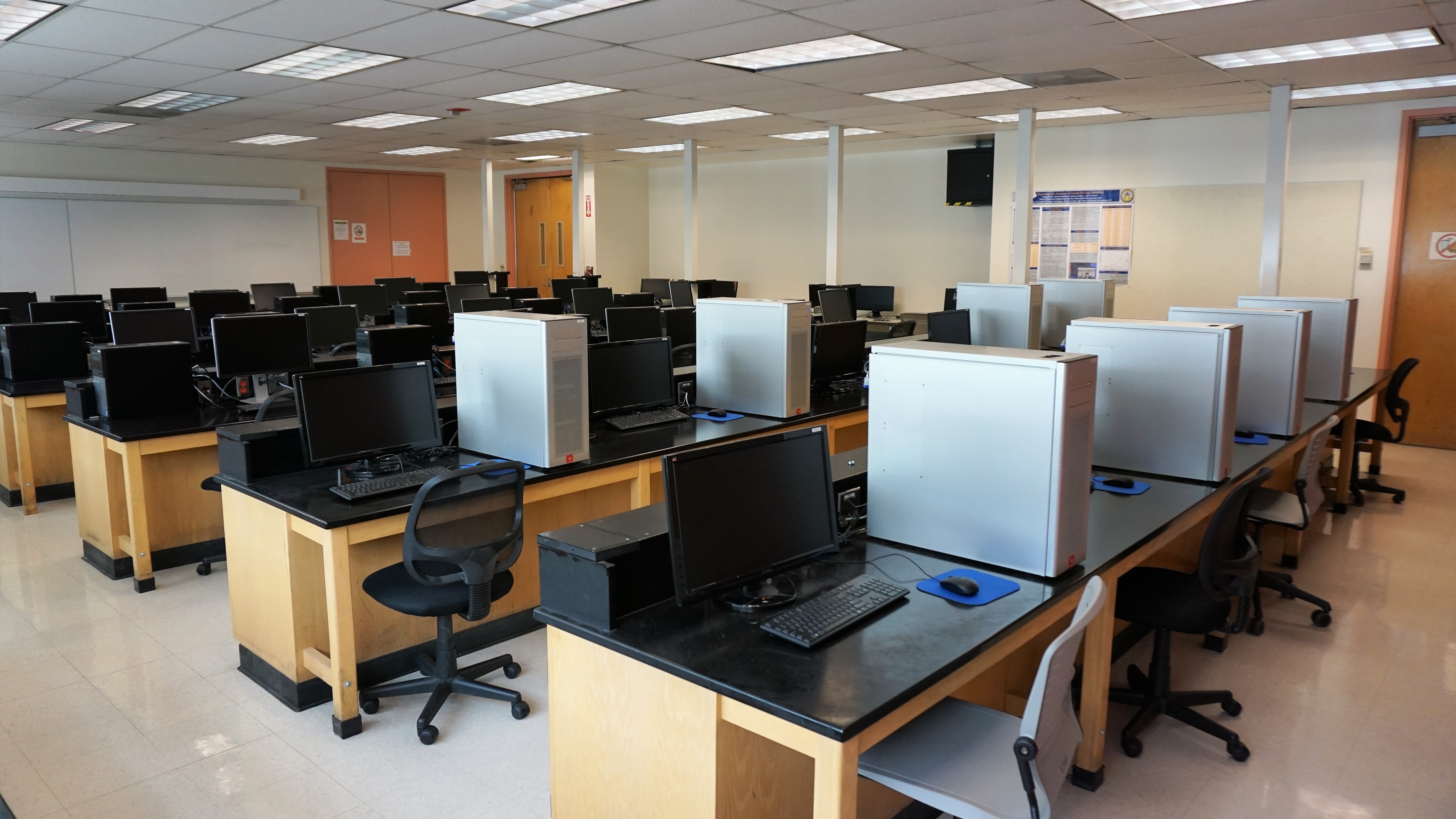 Rows of desks and monitors with large white PCs beside them.