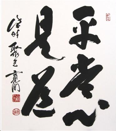 Four Japanese characters written in thick black ink on a white background. They say " The everyday mind is the training ground." The writer's name and two red seals are written vertically to the left of the four characters.