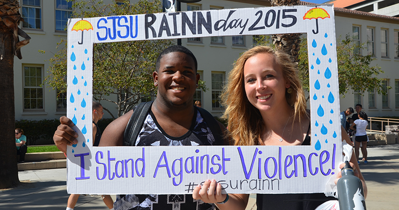 Two students standing with a picture frame SJSU Rain Day 2015