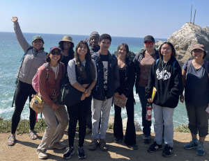 A group of smiling students stending on the beach