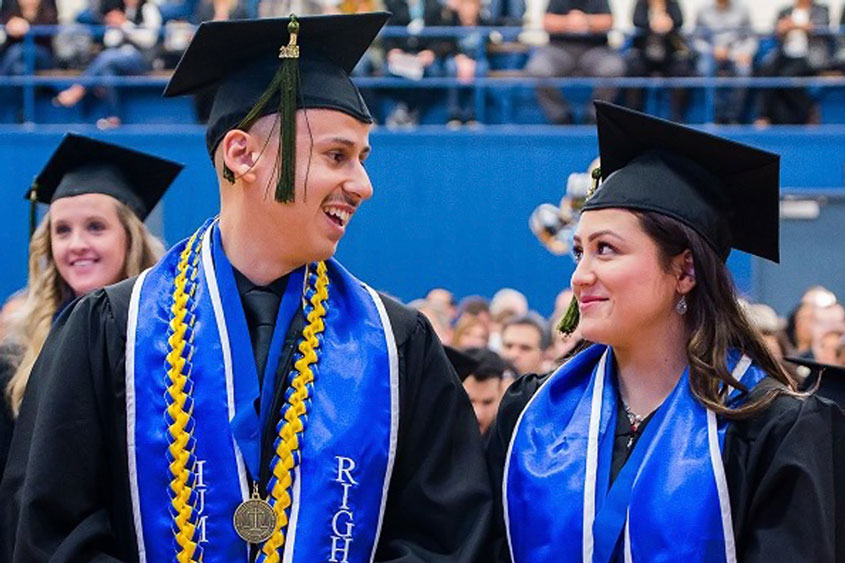 Two HRI graduates look at each other and smile.