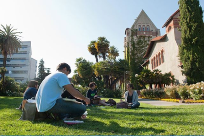 HSPM Students studying on a lawn in fromnt of the SJSU building.