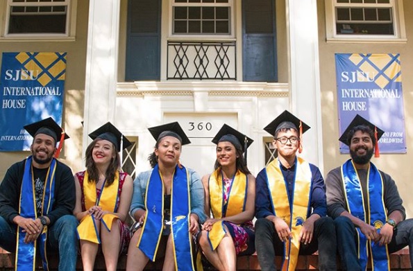 I-House residents seated in front of the building wearing caps and gowns for graduation