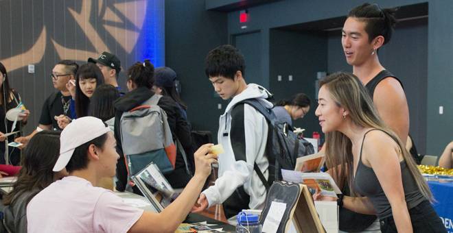 Students talking at an information table during an event