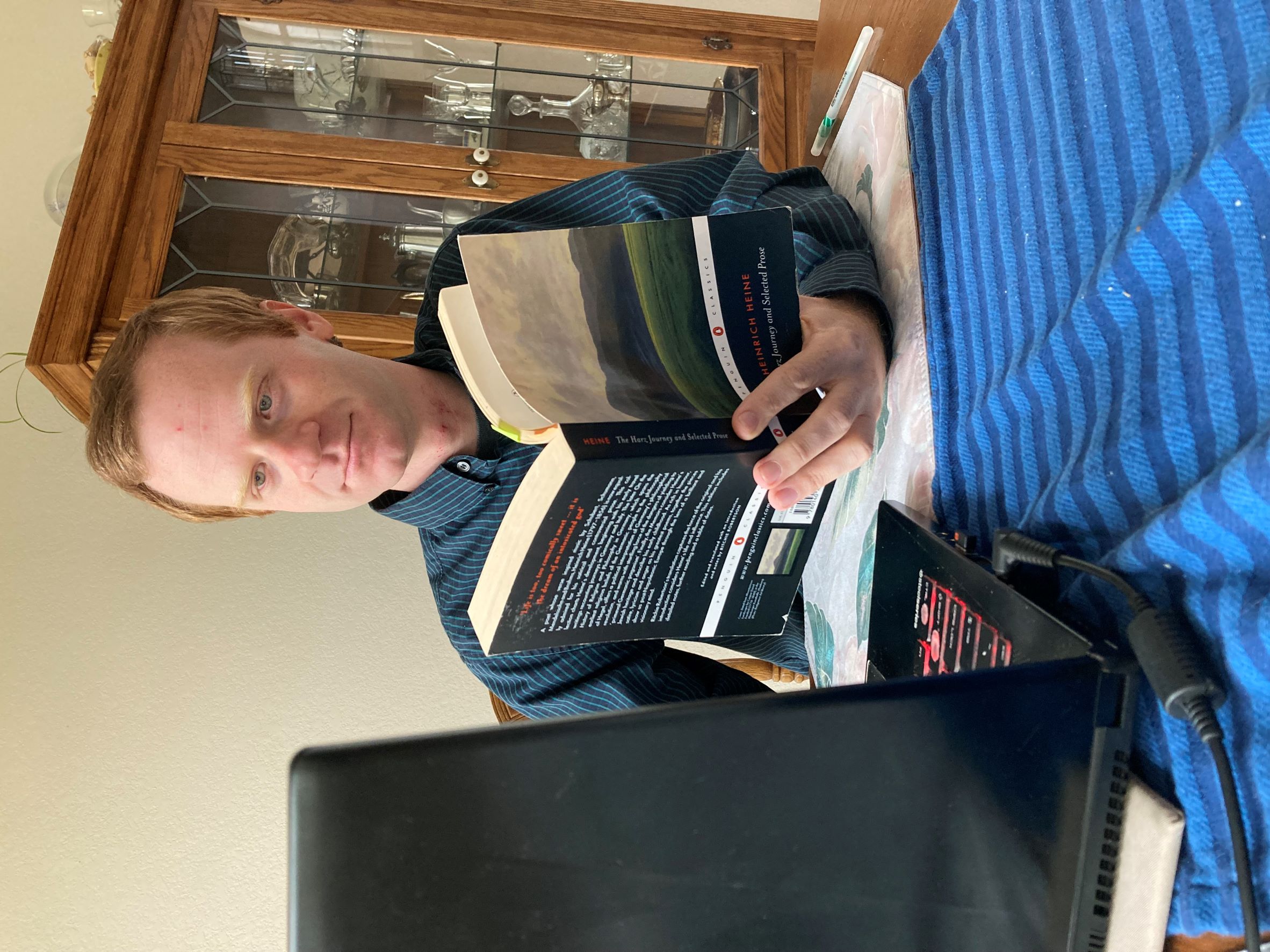 photo of Greg Tomlinson reading a book while looking at his computer screen
