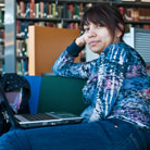 Woman sitting with a laptop on her lap in a library