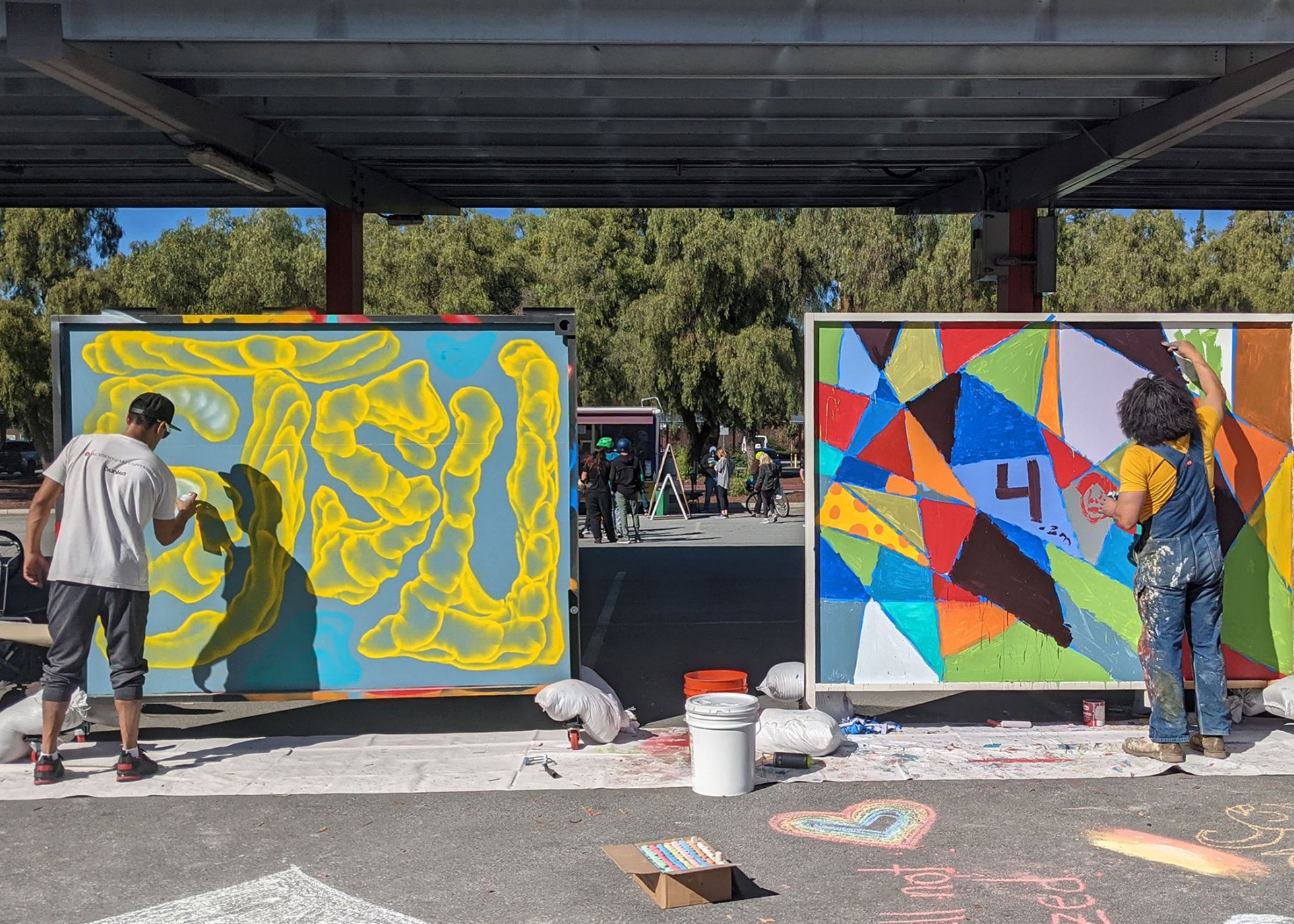 Artists working on their large murals on the street. 
