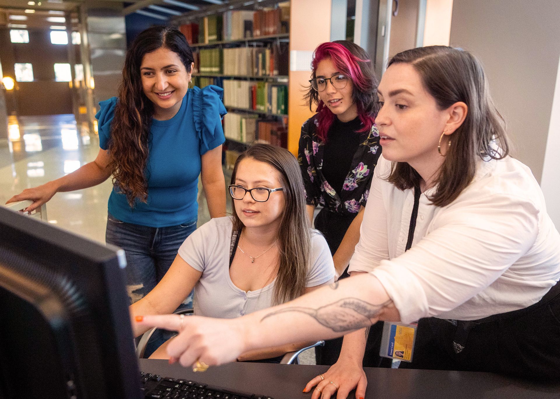 Librarian Anne Marie Engelsen pointing to a computer screen as she talks to students.