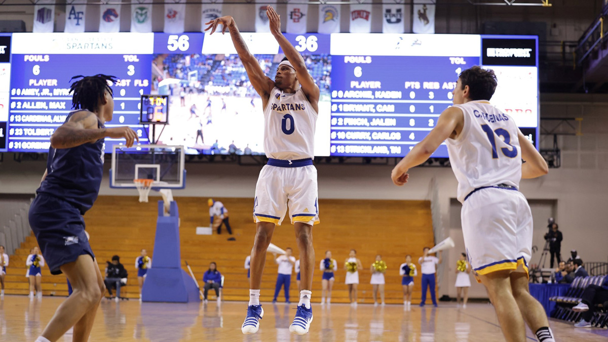 Myron (MJ) Amey in mid air while throwing a basketball during a game.