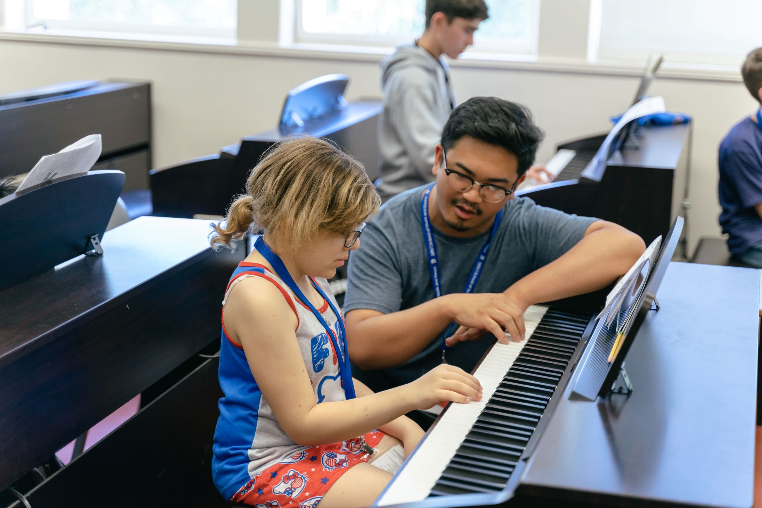 A teacher teaches a young student how to play the keyboard.