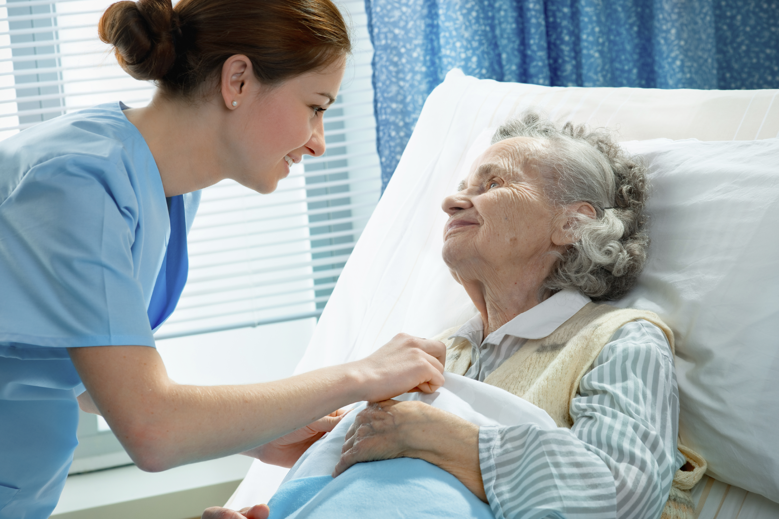 A nurse bedside with an elderly patient.