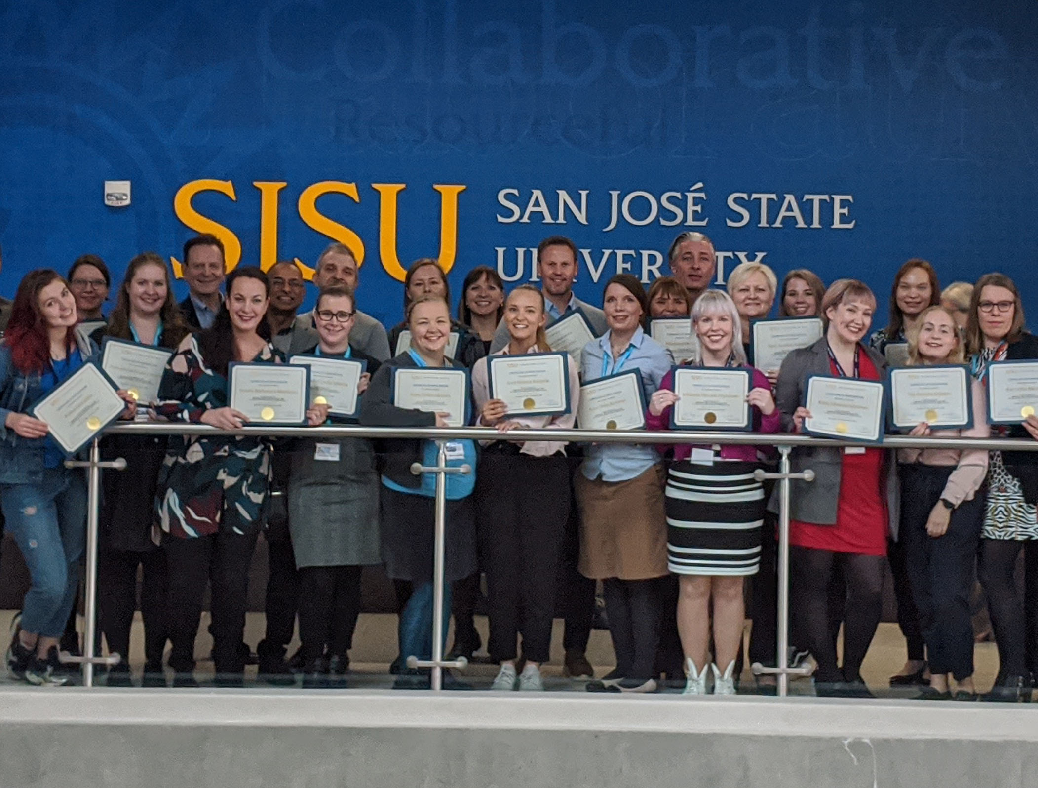 A group of people standing in front of a San José State University sign