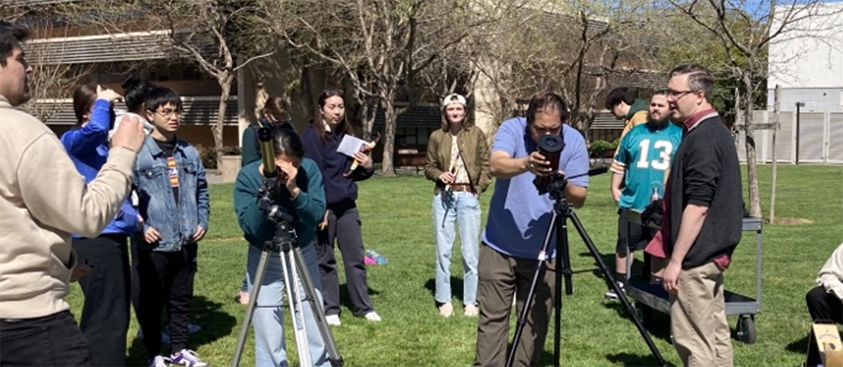 Photograph of students and faculty members using telescopes to view the Sun.