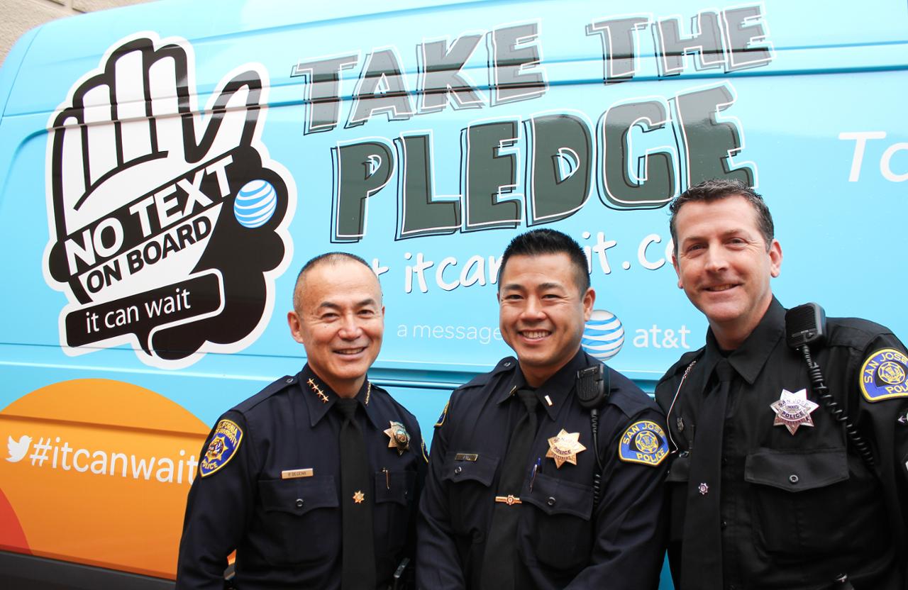 Three male university police officers smile at a safety program event