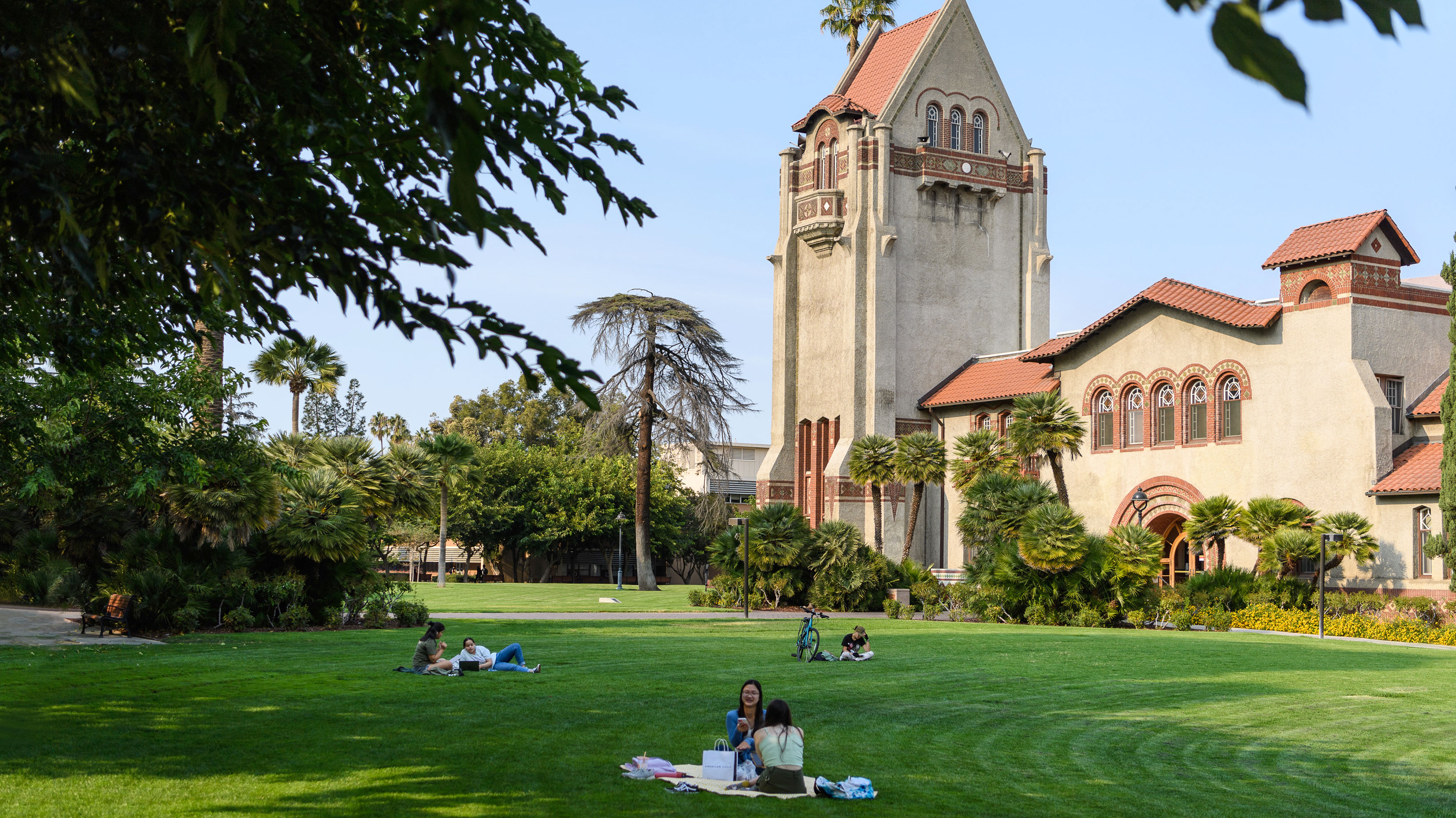 Tower hall on a sunny day with students relaxing on the lawn.