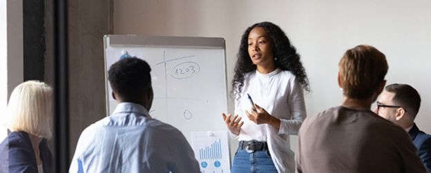 A presenter at a whiteboard speaks to four people