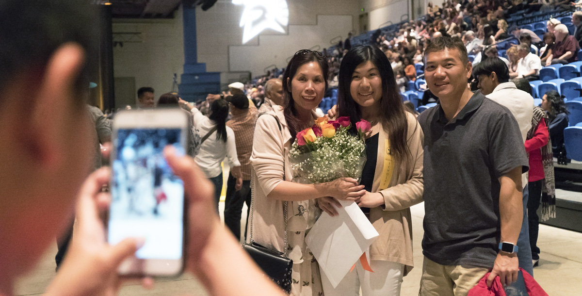 Parents pose with their honor student as someone takes a photo.