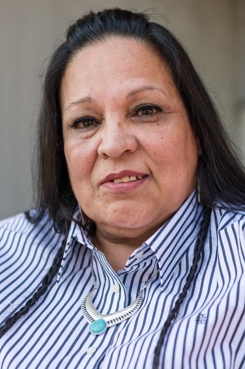 Hispanic woman with a blue, striped button down and a turquoise necklace.