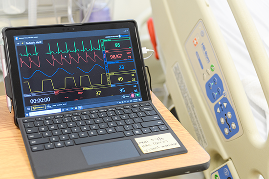 computer screen showing heart monitor information near side of hospital bed