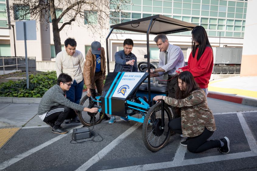 Faculty mentor and students working on a solar-powered bicycle.